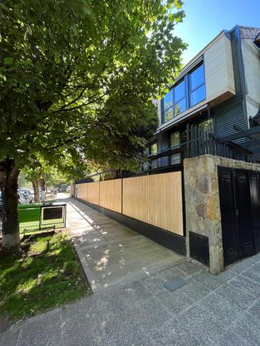 a fence in front of a building with a tree at Monoambiente centrico con jardin in San Martín de los Andes