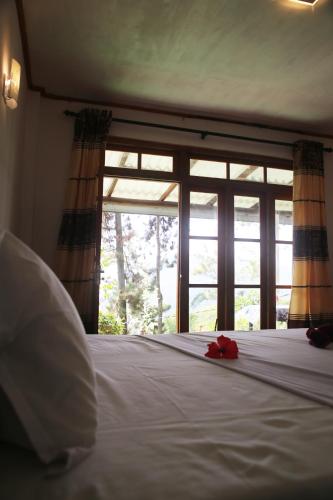 a bedroom with a bed with a large window at Hiruni Cottage Ella in Ella