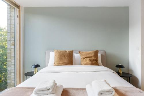 une chambre avec un lit blanc avec des serviettes dessus dans l'établissement GuestReady – Peaceful stay with scenic green views, à Londres