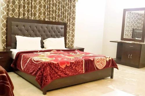 a bedroom with a bed with a red blanket on it at Lahore Luxe Family Couples Guest House in Lahore
