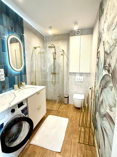 a bathroom with a washing machine and a shower at Apartament River in Pisz