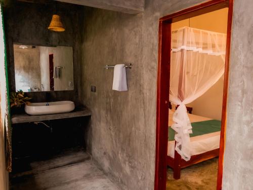 a bathroom with a sink and a bed and a mirror at Dutch House Hiriketiya in Dickwella