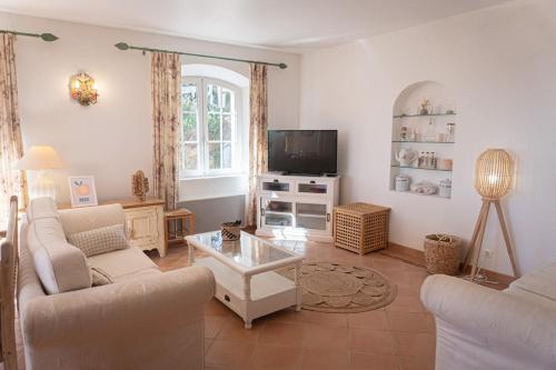 a living room with two couches and a tv at Villa D'arosa - Maison familiale provençale in Ramatuelle