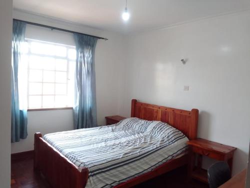 a bedroom with a bed and a window with curtains at Runda Paradise1 in Nairobi