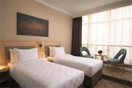 a hotel room with two beds and two chairs at Saja Al Madinah in Al Madinah