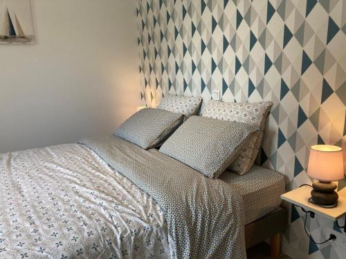 a bed with two pillows and a lamp on a table at Enez terc'h in Plougrescant