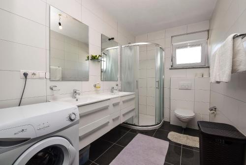 een witte badkamer met een wasmachine bij Mary Rose in Vodice