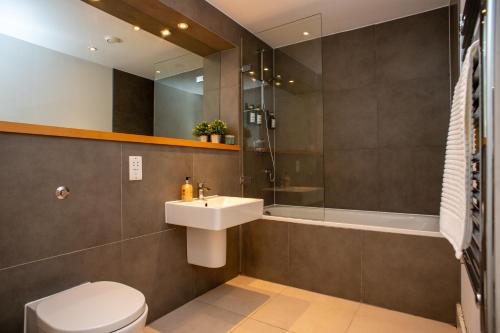 a bathroom with a sink and a toilet and a shower at Luxury cosy apartment with stunning London skyline views! in London