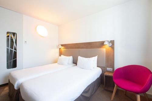 a bedroom with a large bed and a red chair at Campanile Limoges Centre - Gare in Limoges