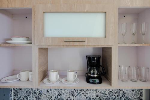 a cupboard with a coffee maker and cups and mugs at Ulala Culebra in Culebra
