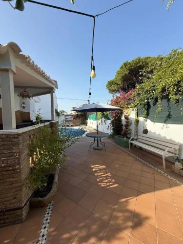 a patio with a table and a bench and an umbrella at Charming Villa in Punta Umbría with Private Pool in Punta Umbría