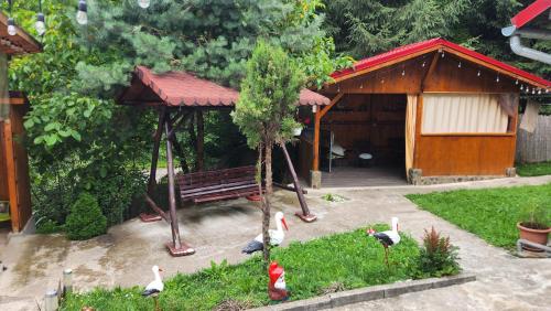 a gazebo with a bench and some birds in the grass at cabana din vale 