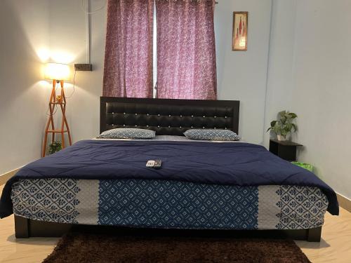 a bedroom with a bed with a blue comforter at Beltola serenity homestay in Guwahati