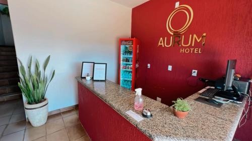 a reception desk in a hotel with a red wall at Aurum Hotel in Água Boa