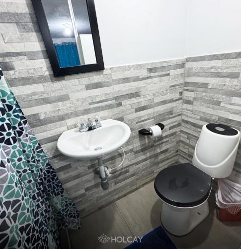 a bathroom with a sink and a toilet and a mirror at Hospedaje Holcay in Bogotá