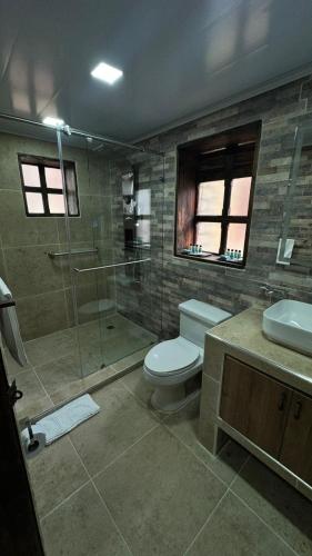 a bathroom with a toilet and a shower and a sink at Hotel Boutique Guatika in Tibasosa