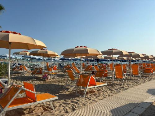 a row of chairs and umbrellas on a beach at Hotel Haus Charlotte in San Benedetto del Tronto