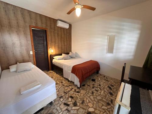 a hotel room with two beds and a ceiling fan at No Worries Pipa in Pipa