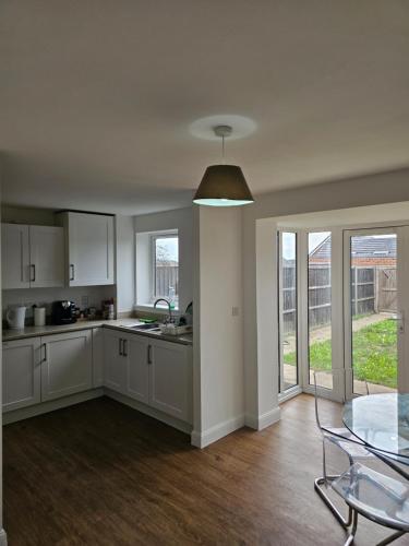 a kitchen with white cabinets and a glass table at Double Cosy bedroom in central Dartford-Close to all amenities in Dartford