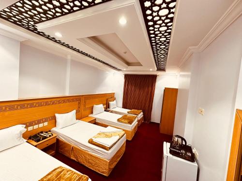a hotel room with three beds in a room at فندق غزالة برفكت توصيل مجاني للحرم - Ghazala Perfect Hotel Free shuttle service to the Haram in Makkah