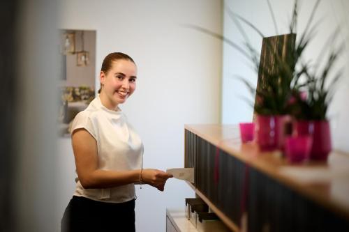 a woman standing next to a counter holding a piece of paper at Hotel Gasthof Krönele in Lustenau