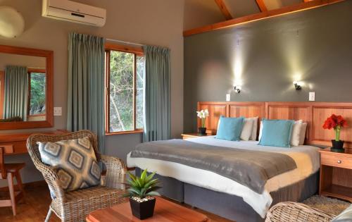 a bedroom with a large bed and a chair at eBundu Lodge in White River