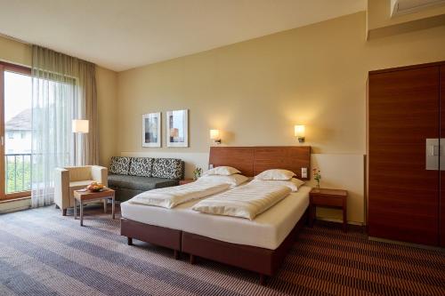 a bedroom with a large bed and a couch at Hotel Gasthof Krönele in Lustenau