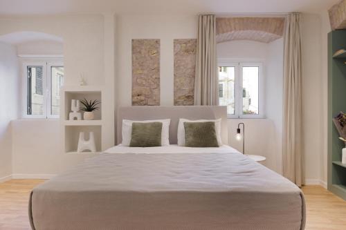 ein weißes Schlafzimmer mit einem großen Bett mit zwei Kissen in der Unterkunft Dousmani Old Town Studio in Korfu-Stadt