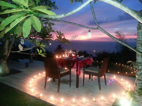 a table and chairs on a deck with lights at The Puncak Lombok in Senggigi 