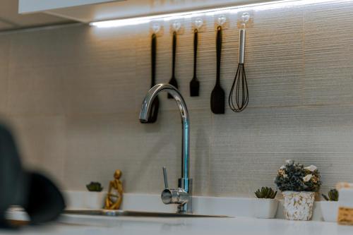 a kitchen sink with utensils hanging on a wall at Modern Glass Suite with City Views Reem Island in Abu Dhabi