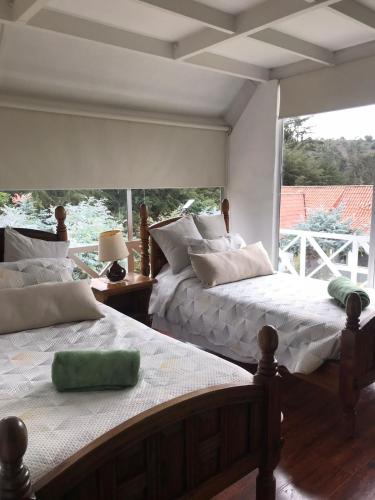 two beds in a room with a large window at Chalet Andino Sesquile in Suesca