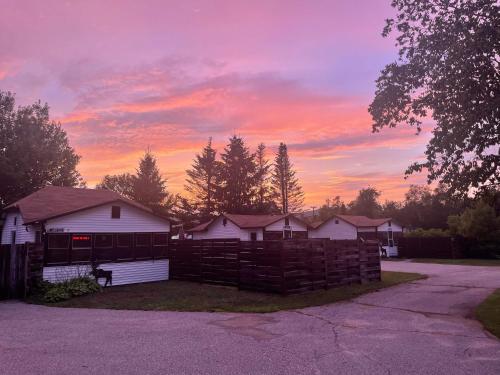 a house with a fence in front of a sunset at Hike the Presidential's & Relax in the Hot tub #6 in Carroll