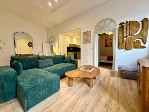 Una sala de estar con un sofá verde y una mesa. en Suite Madeleine - Cœur Historique, en Béziers