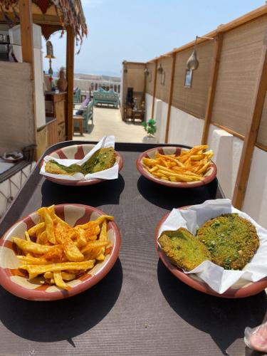 three plates of food on a table with french fries at Ghazala Oasis Hotel in Dahab