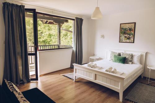 a bedroom with a white bed and a large window at Wildwood Villa in Apriltsi