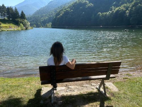 a woman sitting on a bench next to a lake at Suite Romantica Fuga in Roncone