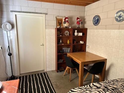 a room with a table and chairs and a book shelf at Simpel overnachten in Langeveen