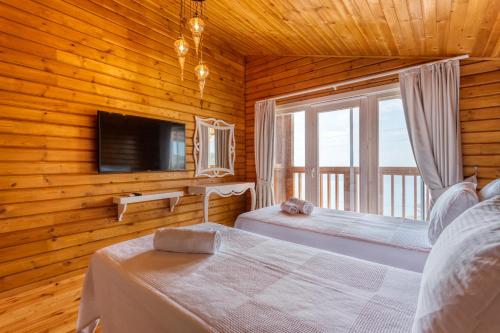 a bedroom with two beds and a television in a log cabin at Eco Villa BEGONVİL in Kalkan