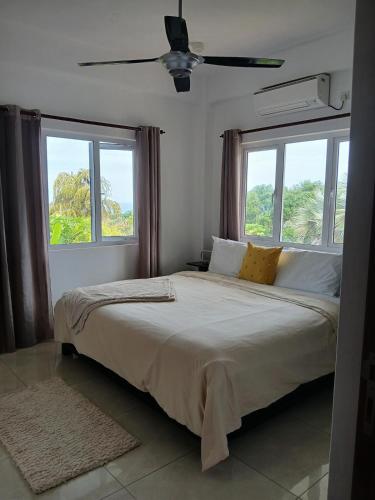 a bedroom with a large bed with two windows at Royale Green Villa in Anse Royale