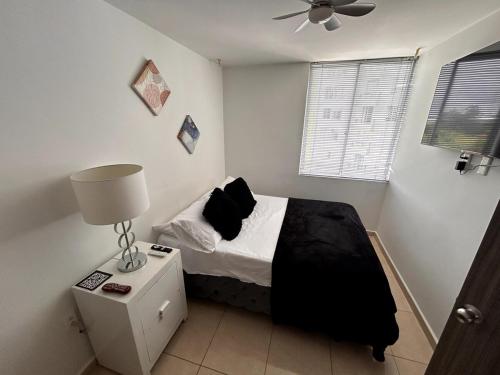 a bedroom with a bed with a black blanket and a lamp at Ven y Escapate al Quindío in Estación El Salto