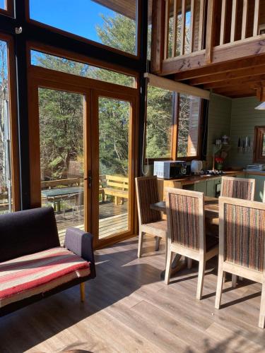 a dining room with a table and chairs and windows at Lofts Magnolias in Puerto Varas