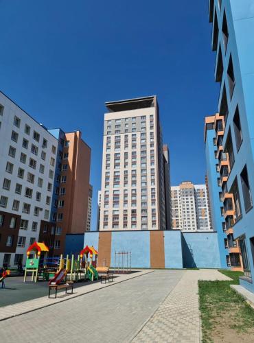 a park with benches in a city with tall buildings at Уютные Апартаменты в ЖК Life Park in Astana