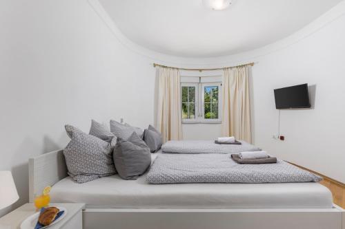 Un dormitorio blanco con una cama grande y una ventana. en Villa Alex, en Crikvenica