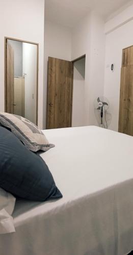 a white bed with a black pillow and a mirror at Alojamientos ejecutivos y modernos en condominio privado in Aguachica