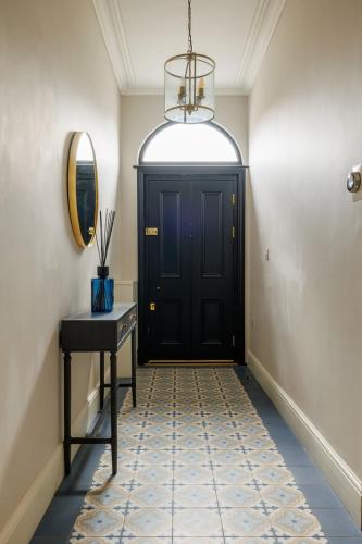 a hallway with a black door and a table and a mirror at GuestReady - Contemporary home with garden in Dublin