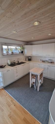 a kitchen with white cabinets and a wooden ceiling at Holiday home close to forest, lake and skiing in Ulricehamn