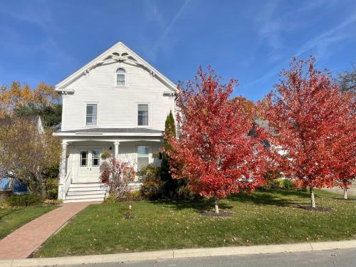 a white house with red trees in front of it at Falls Farmstead 1865 Ellis House - Apt 3 in Ellsworth