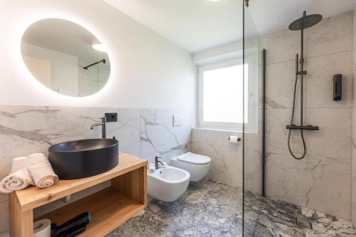 a bathroom with a sink and a toilet and a mirror at Boutique Hotel Pradell in Ortisei