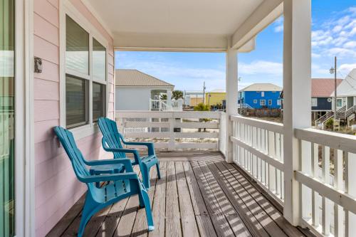 twee blauwe stoelen op de veranda van een roze huis bij Bikini Bottom in Gulf Shores