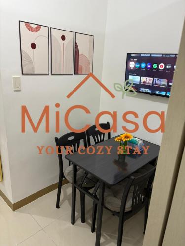 a black table and chairs in a room with a sign at MiCasa South Residences Cozy & Affordable Stay in Manila